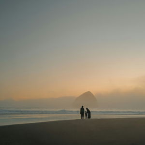Family walking on a foggy beach at sunset